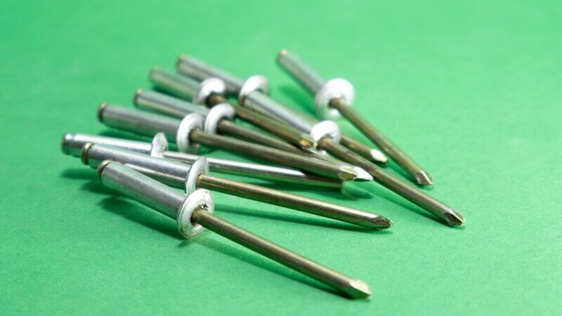 A pile of metal rivets on a green background